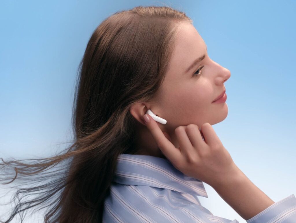 Eine Frau greift zu ihrem Ohr. Sie trägt die Huawei FreeBuds 2 SE Kopfhörer.