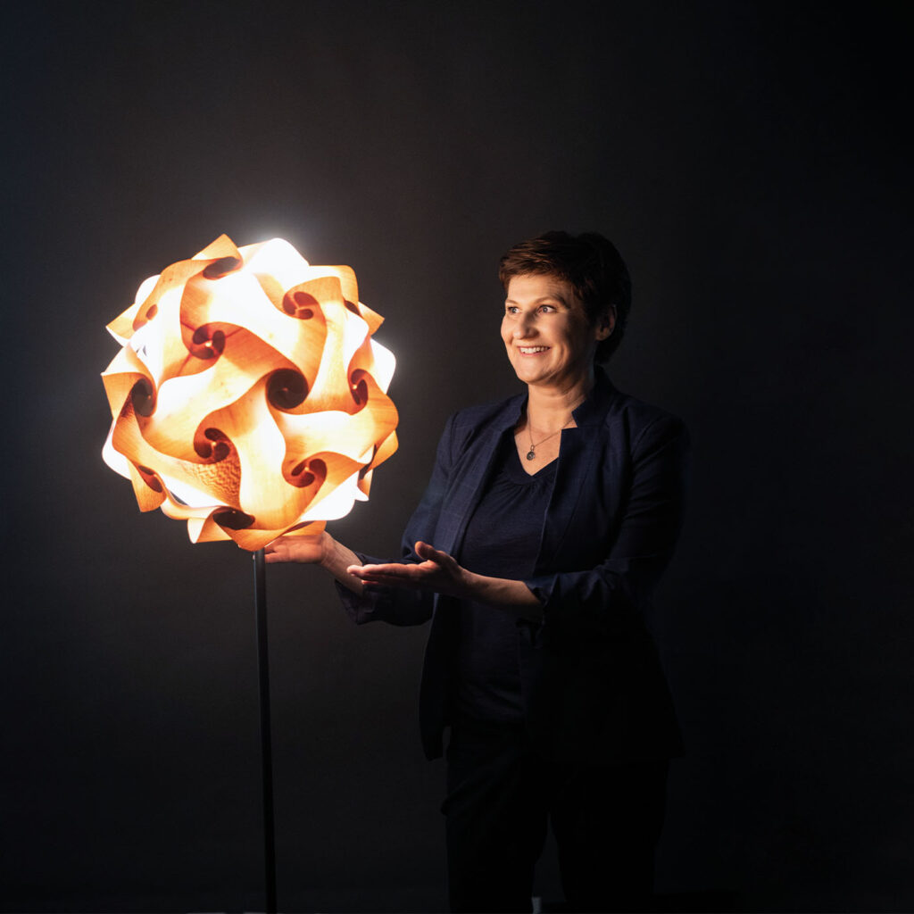 Licht Designerin Birgit Sargant vor einer schwarzen Leinwand präsentiert einer Ihrer neuen Leuchten