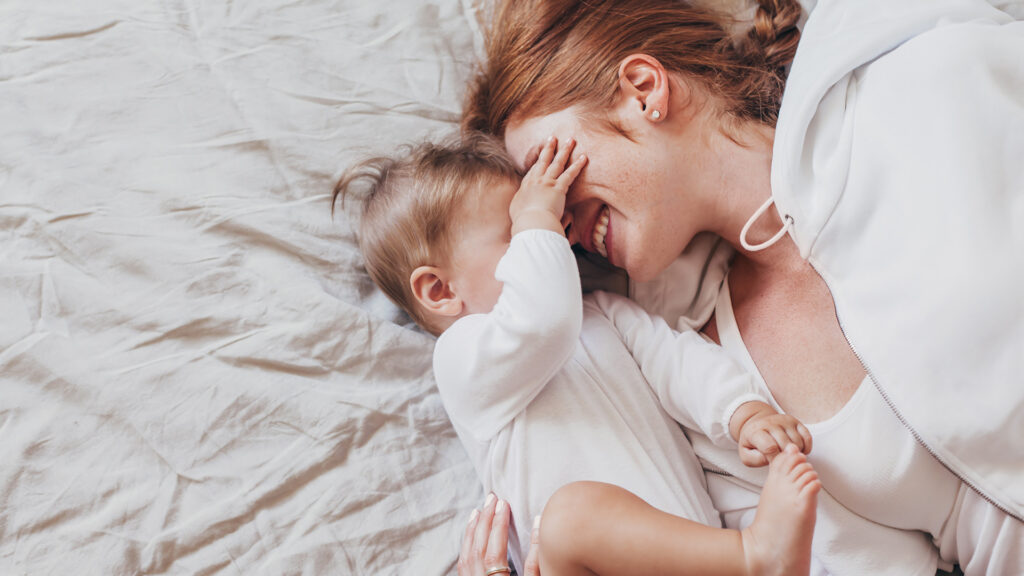 Mom Lifehacks: Baby kuschelt mit rothaariger Mama und hat die Hand auf ihren Augen