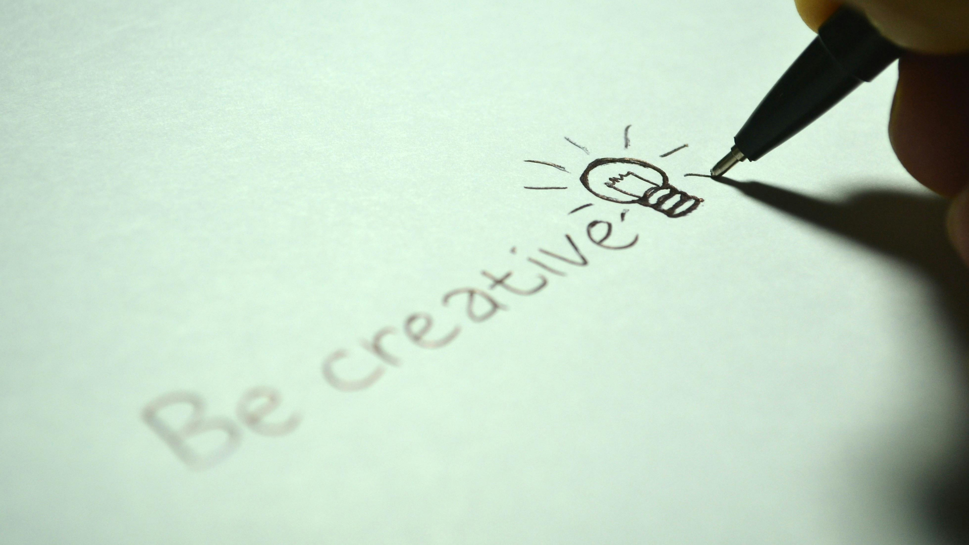 Die Rolle von Kreativität in der modernen Geschäftswelt und wie man sie fördert; Eine Hand schreibt be creative