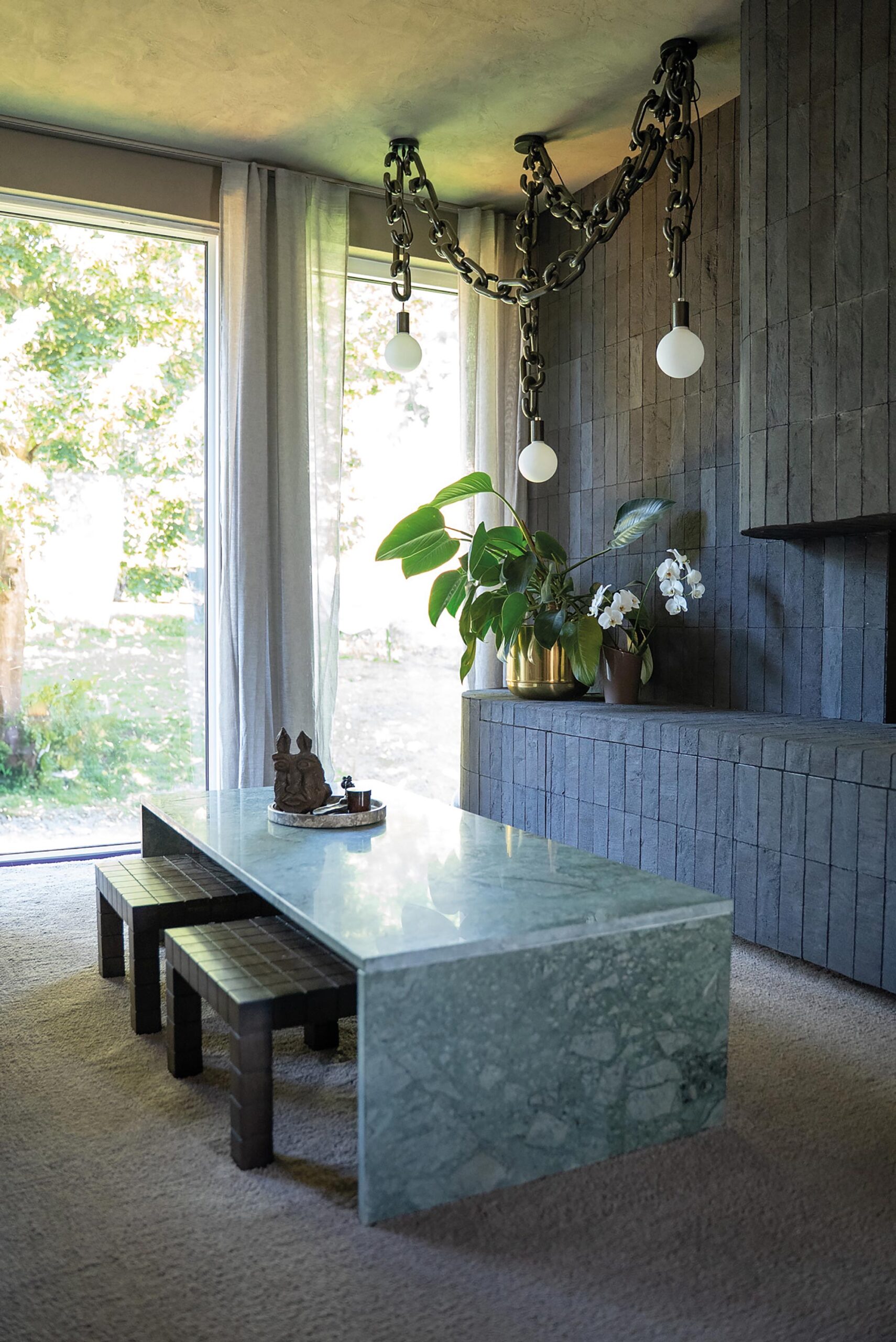 Moderner Wohnraum mit Steintisch und hängender Ketten-Leuchte.