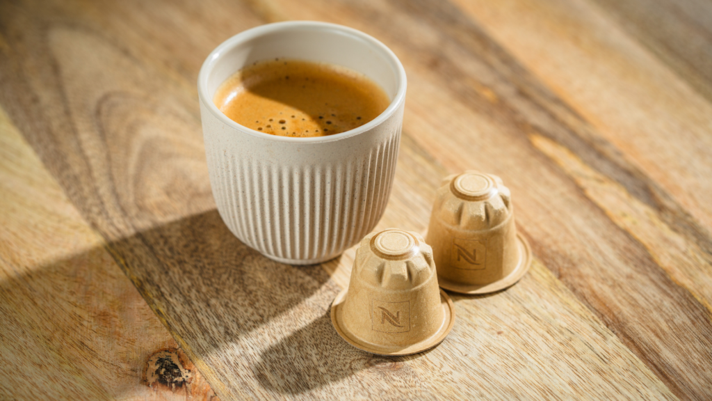 Eine Tasse Kaffee, davor liegen zwei Papierkapseln von Nespresso