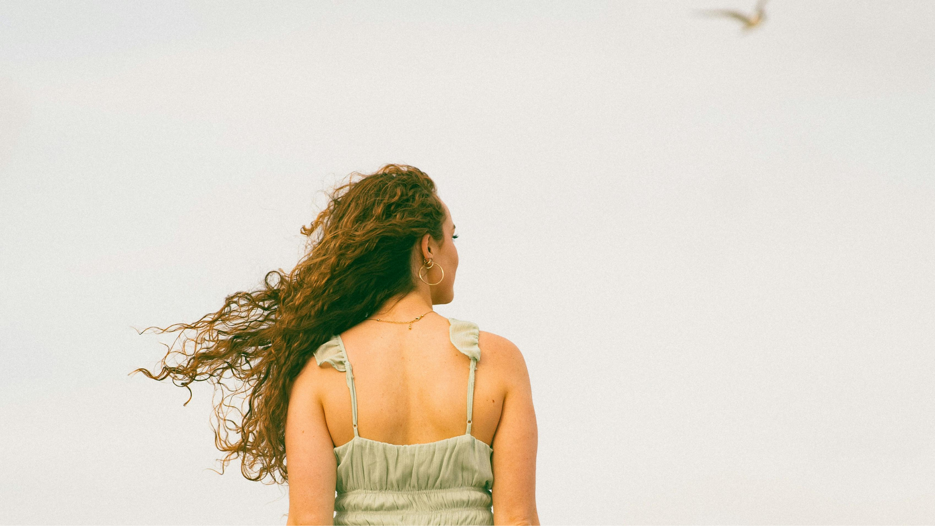 Frau mit zugekehrtem Rücken blickt in die Ferne