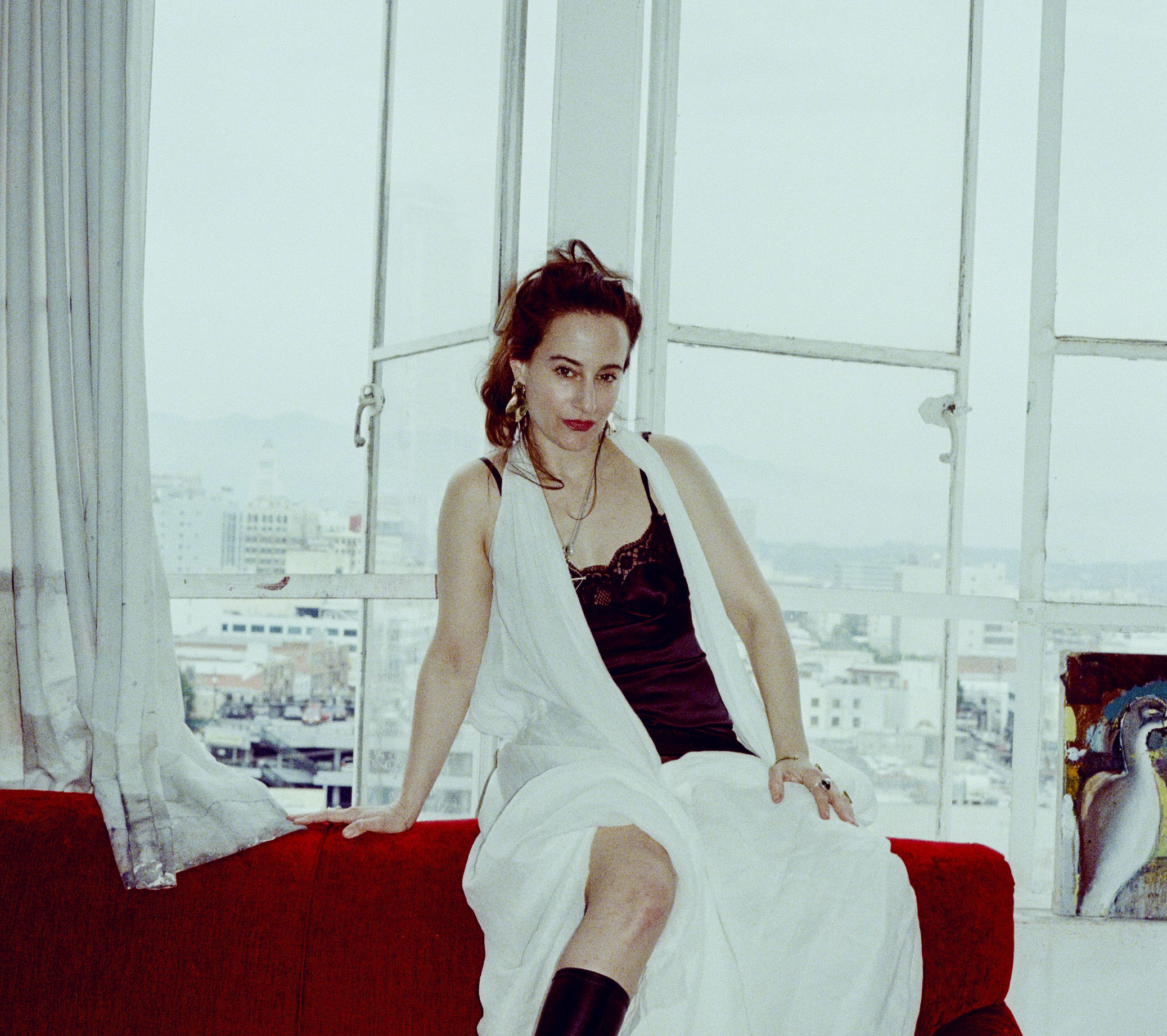 Portrait von Katherina Olschbaur auf einem roten Samtsofa sitzend.