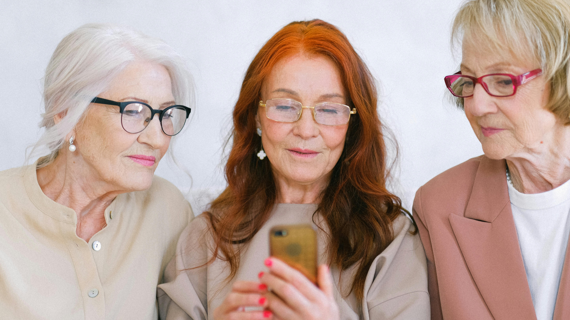 Drei Frauen schauen auf ein Handy, das die Frau in der Mitte hält