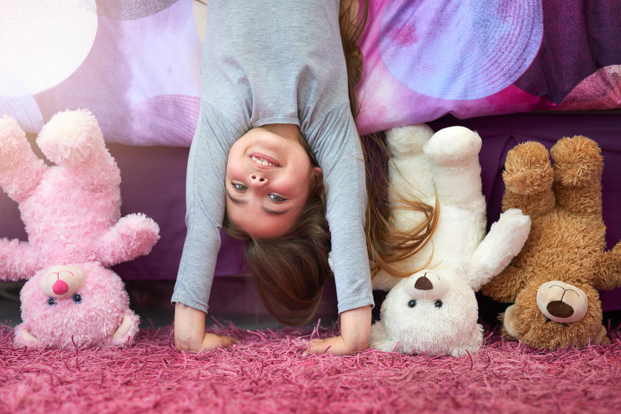 Langeweile Kinder: Lachendes Mädchen steht mit Kuschelbären Kopf.