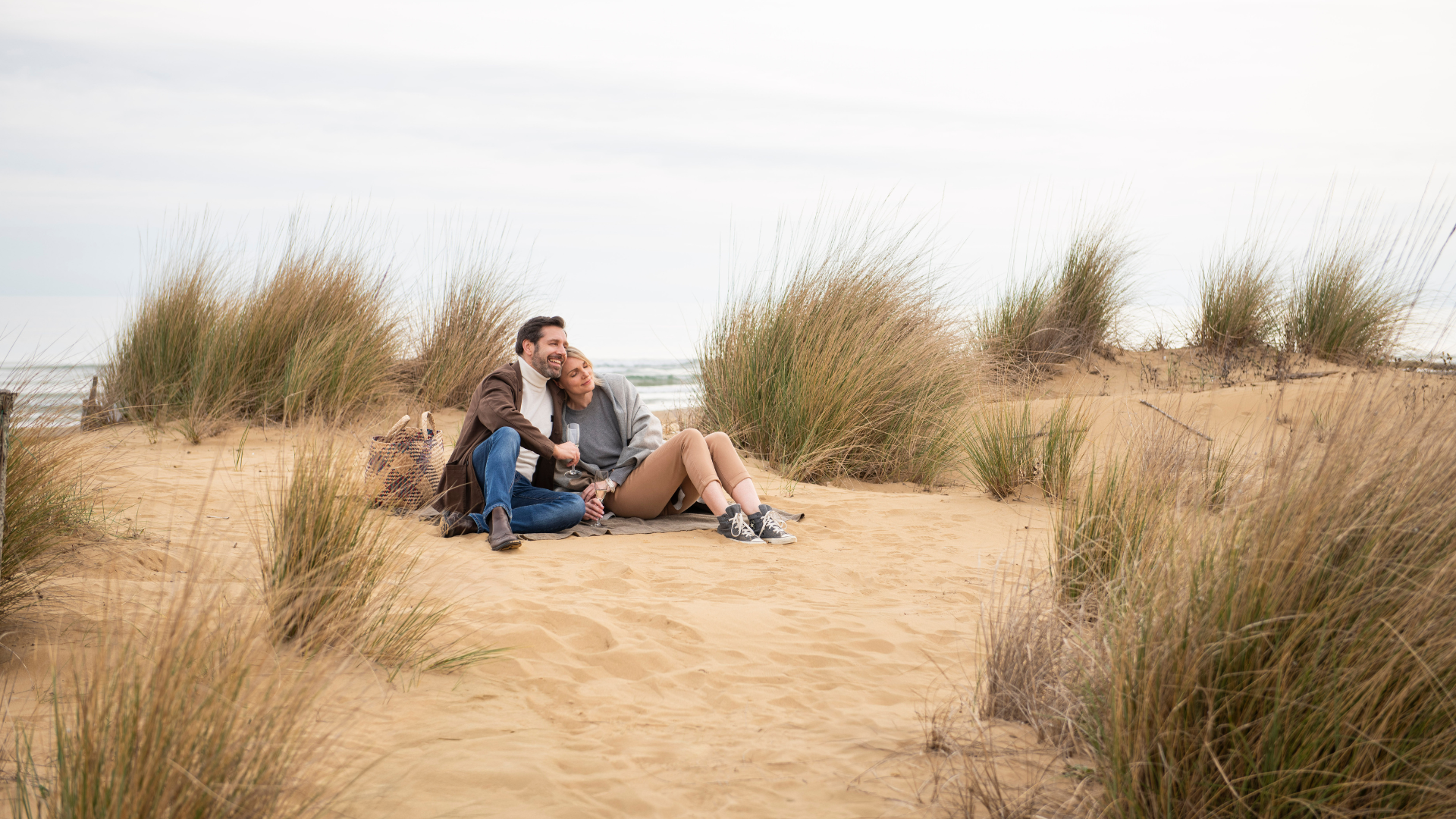 Ein Mann und eine Frau kuschelnd und lachend in den Dünen